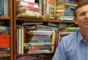 One man standing in front of a wall of books.