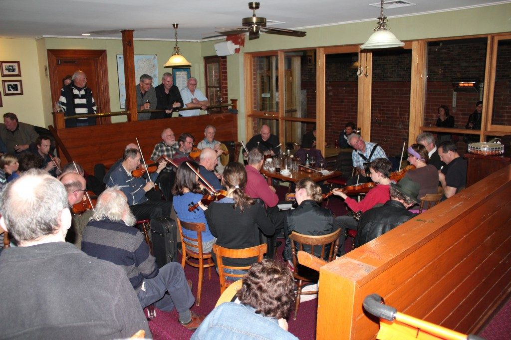 A small group of people playing violins at the Corkman