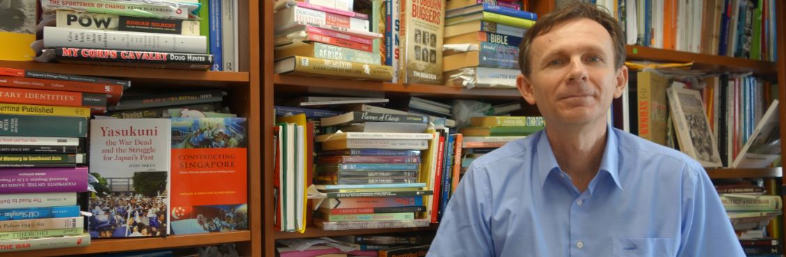 One man standing in front of a wall of books.